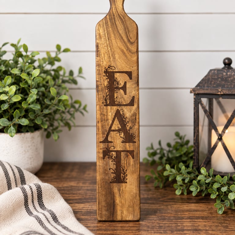 Tall wooden paddle board engraved vertically with the word EAT